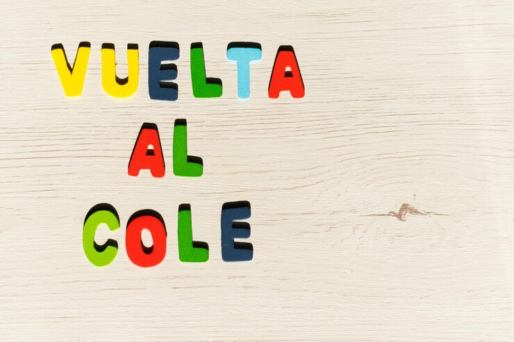 Foto letras de colores con la palabra en español vuelta al cole sobre un fondo de madera en colores claros y sp.
