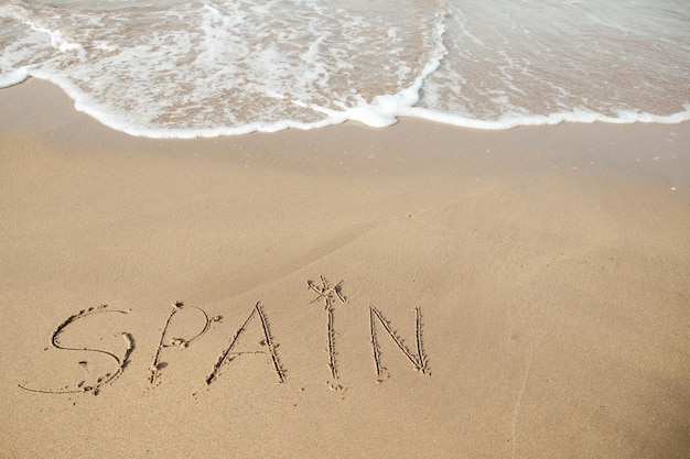 Letras de Espanha na praia de areia e água do mar