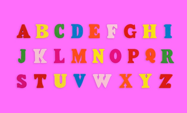 letras de madeira do alfabeto inglês multicoloridas sobre um fundo rosa