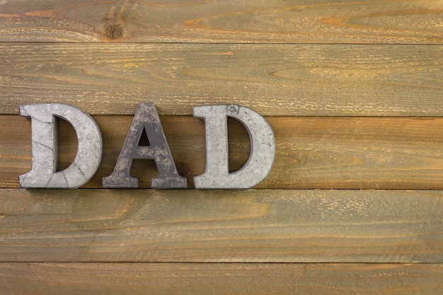 Letras de metal PAI em um fundo de madeira pintado.