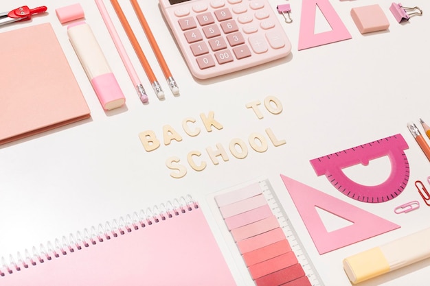 Letras de volta à escola em um fundo rosa com material escolar