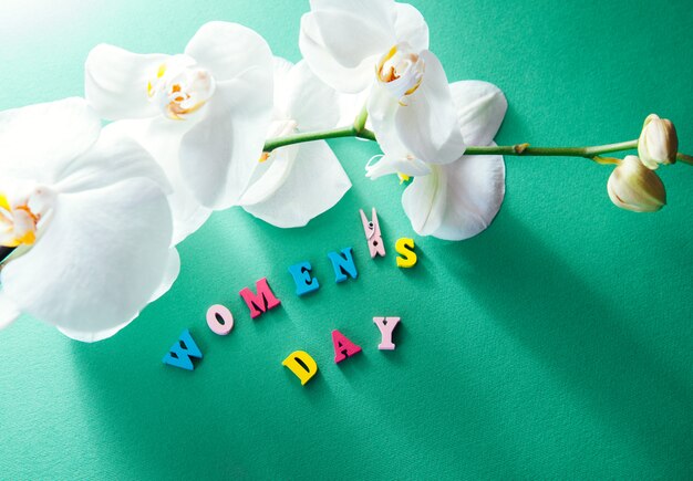 Letras del día de la mujer con orquídea blanca