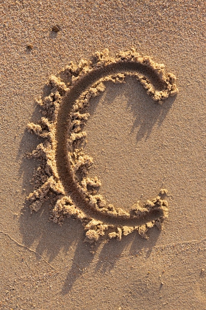 Foto letras do alfabeto (c) escritas à mão na areia na praia