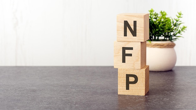 Letras do alfabeto de NFP em cubos de madeira verde planta fundo branco NFP curto para NonFarm Payroll