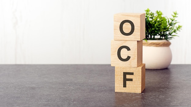 Letras do alfabeto de ocf em cubos de madeira verde planta fundo branco