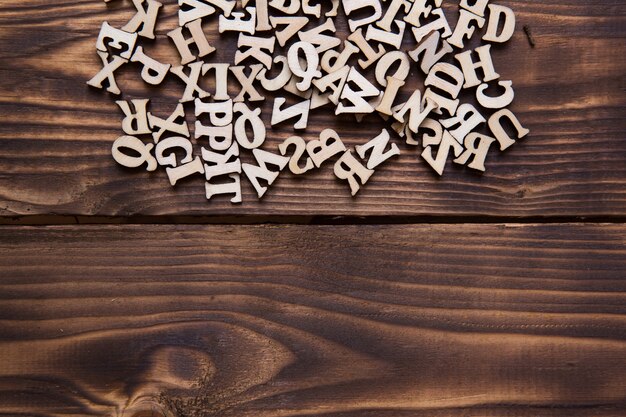 Foto letras do alfabeto inglês em um fundo escuro de madeira. o conceito de educação, jogos de palavras, bordado. espaço para texto