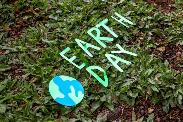 letras do dia da terra com globo do mundo sobre fundo de grama verde natural.