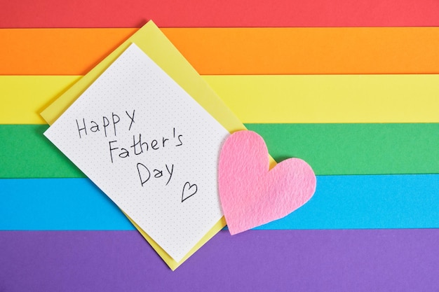 Letras feliz día del padre en papel postal de corazón de fieltro y sobre en el espacio de copia de vista superior de fondo de arco iris