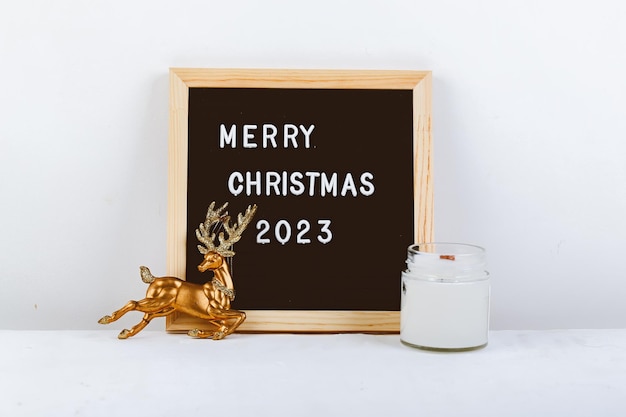 Letras de feliz Navidad en el tablero de cartas Eco árbol y ciervo dorado fondo minimalista de año nuevo 2023