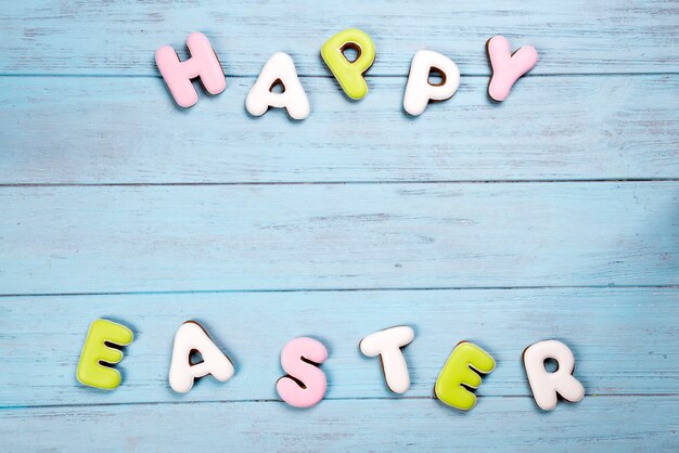 Letras de galletas feliz Pascua sobre fondo azul de madera.