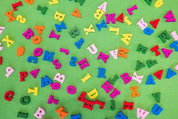 Las letras inglesas de colores se encuentran dispersas al azar sobre un fondo verde. Fondo del alfabeto inglés.