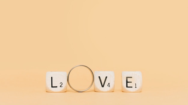 Foto letras de madera y amor de deletreo de anillo de compromiso sobre fondo beige