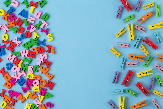 Letras de madera multicolores y pequeñas pinzas de madera sobre fondo azul.