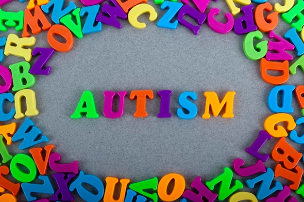 Letras multicolores y la palabra autismo sobre un fondo gris