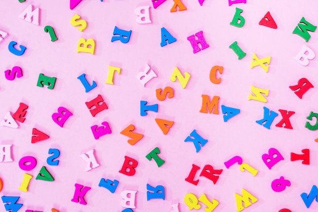 Letras multicoloridas do alfabeto inglês em um fundo rosa, fundo de letras. conceito de educação.
