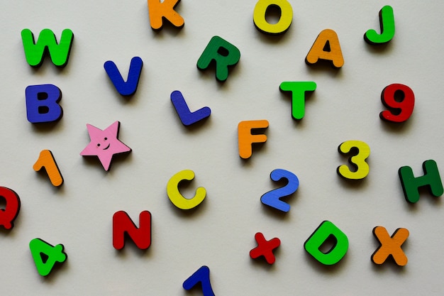 Letras y números multicolores de madera sobre un fondo beige. Juego educativo para la escuela primaria. Día del Niño.