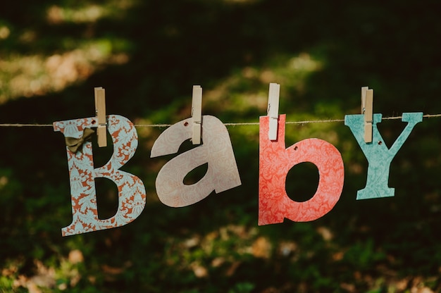 Foto letras de la palabra bebé y calcetines de punto colgando en la cuerda para tender la ropa