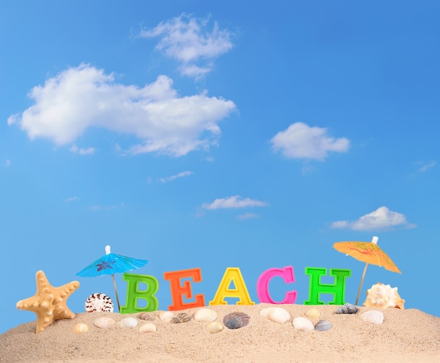 Letras de playa en la arena de una playa contra el cielo azul