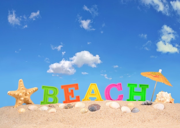 Letras de playa en la arena de una playa contra el cielo azul