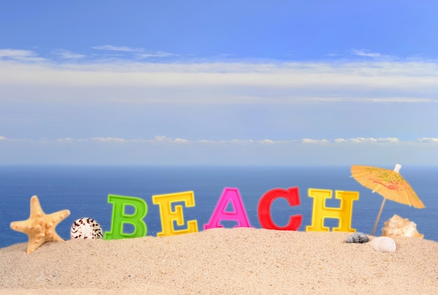Foto letras de playa en la arena de una playa con el fondo del mar