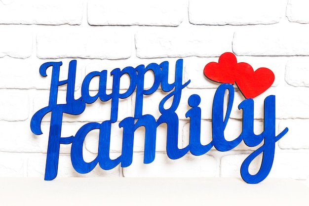 Letrero decorativo azul y rojo que dice Familia Feliz colocado contra una pared de ladrillo blanco