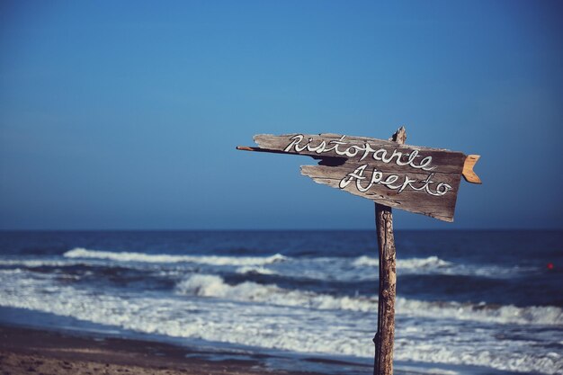 Letrero de información en la playa contra un cielo despejado