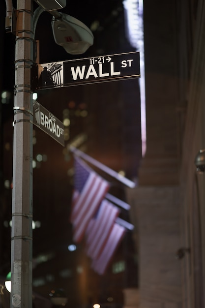 Foto los letreros de broadway y wall street en la noche con banderas estadounidenses en el fondo, manhattan, nueva york