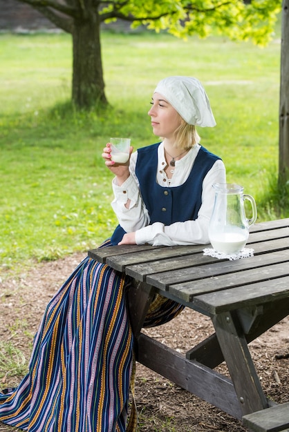 Lettische Frau in traditioneller Kleidung mit Milchglas auf Naturhintergrund im Dorf Riga Lettland