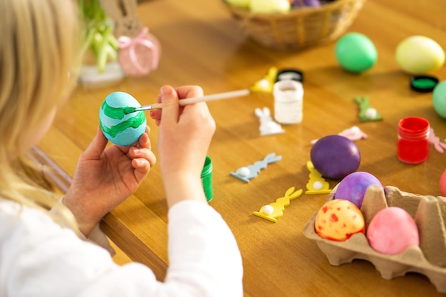 Lettle manos de niños pintando huevos de Pascua en la mesa de madera Preparación para la celebración de Pascua