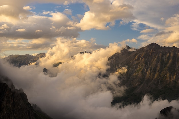 Letztes warmes Sonnenlicht auf Alpental mit glühenden Bergspitzen und szenischen Wolken