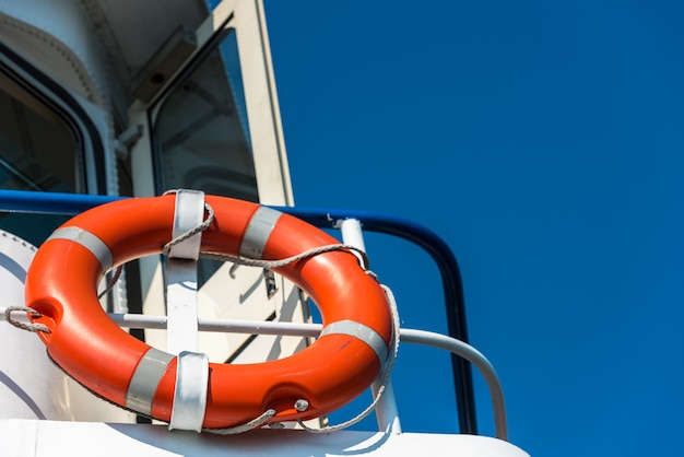 Leuchtend orange Rettungsring auf einer weißen Yachtseite.