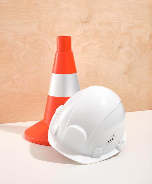 Leuchtend orangefarbener Baukegel und weißer Bauhelm zum Schutz beim Bau und bei harter Arbeit