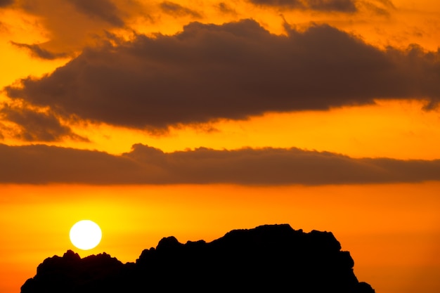 Leuchtend orangefarbener Sonnenuntergangshimmel über Klippe