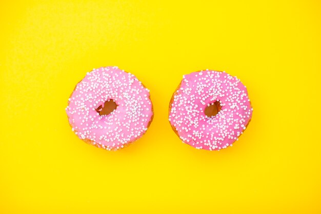 Leuchtend rosa leckere Donuts auf einem Gelb