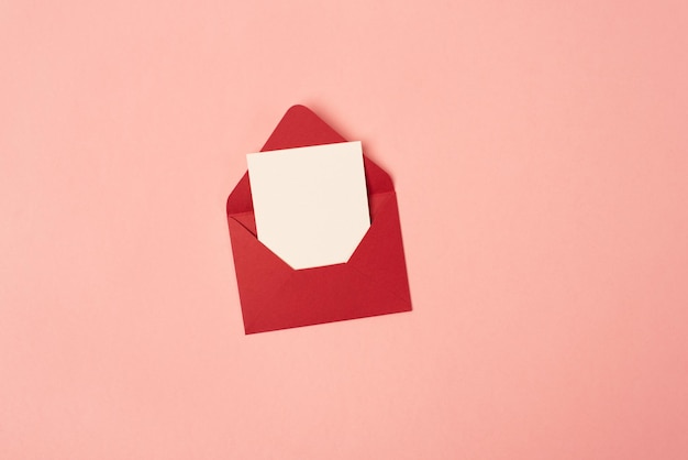 Leuchtend roter Umschlag mit einem leeren Blatt Papier auf rosa Hintergrund Kopieren Sie Platz für Text