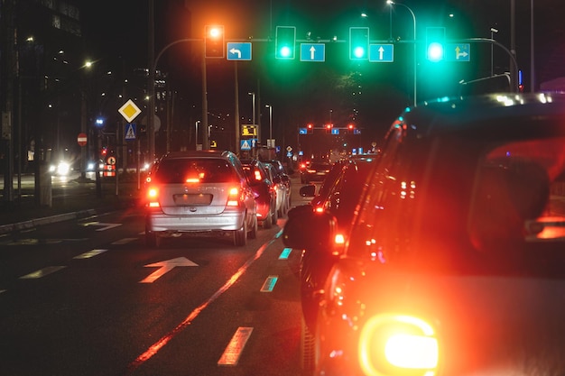 Leuchtende Ampeln und Scheinwerfer von Autos am Abend im Stadtverkehr