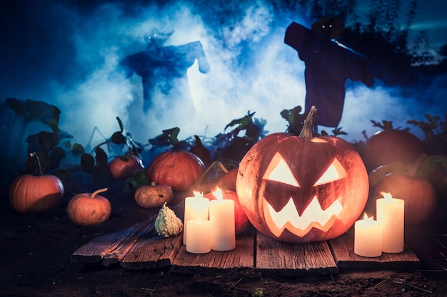 Leuchtender Kürbis mit blauem Nebel und Vogelscheuchen für Halloween