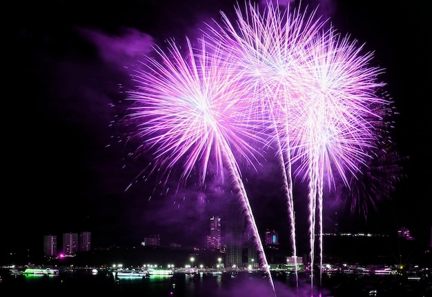 Leuchtendes rosa und lila Feuerwerk plätschert am Nachthimmel über der Stadt