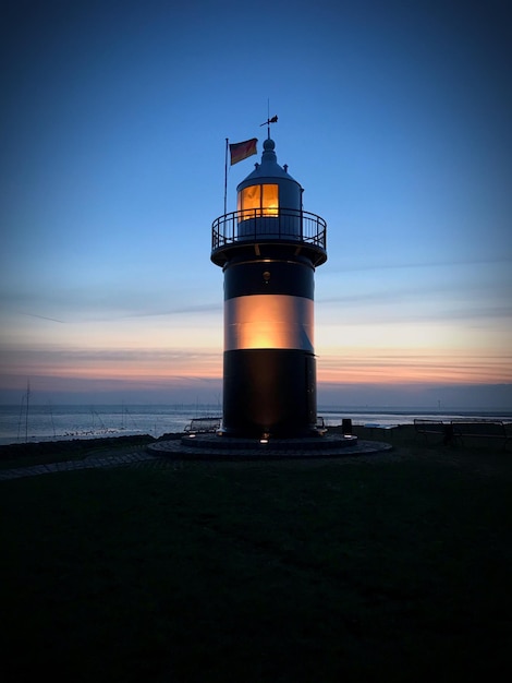 Leuchtturm am Meer gegen den Himmel beim Sonnenuntergang