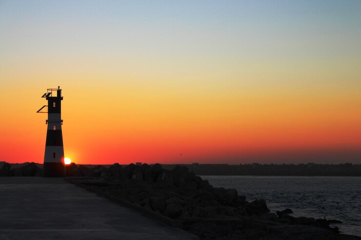Foto leuchtturm am meer gegen den romantischen himmel beim sonnenuntergang