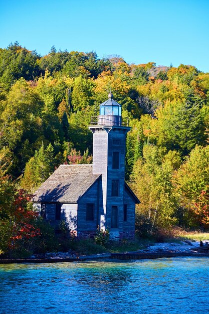 Leuchtturm am Ufer des Lake Superior mit vernagelten Fenstern und grünem Wald dahinter