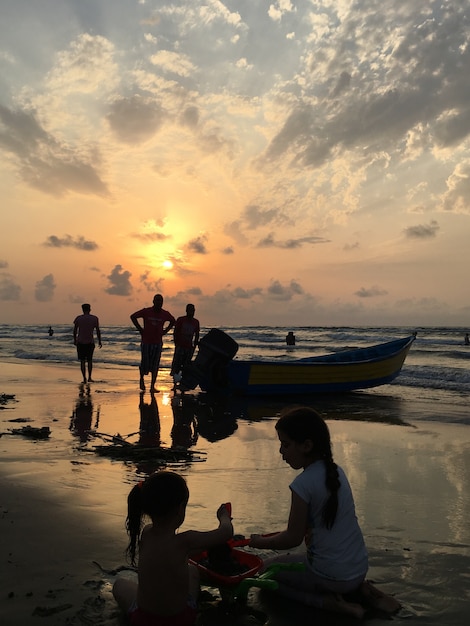 Leute auf Seestrand bei dem Sonnenuntergang, der Spaß hat