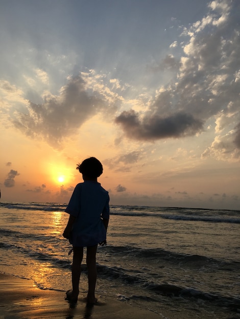 Leute auf Seestrand bei dem Sonnenuntergang, der Spaß hat