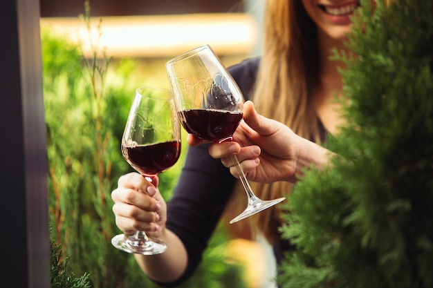 Leute, die auf der Sommerterrasse des Cafés oder Restaurants mit Wein anstoßen. Fröhliche fröhliche Freunde feiern Sommer- oder Herbstfest. Schuss von Menschenhand, Lifestyle hautnah.