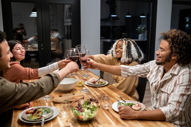 Leute, die bei der Dinnerparty mit Wein anstoßen