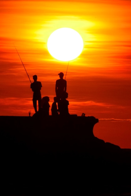 Leute, die den Sonnenuntergang am Strand beobachten