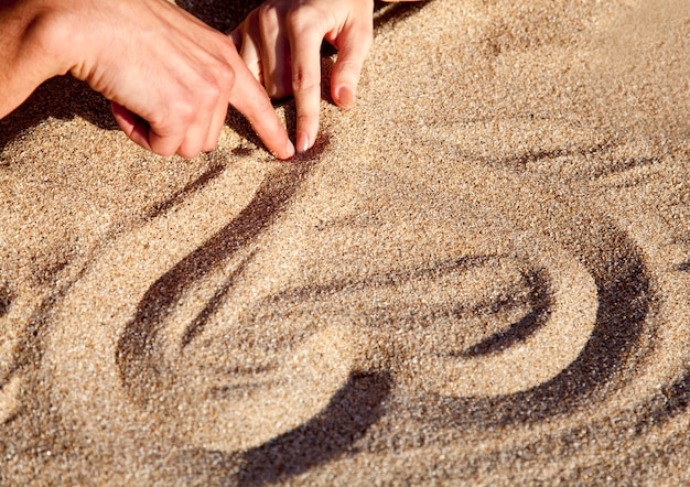 Leute, die Herz am Sand zeichnen