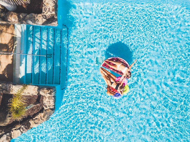 Leute, die im Sommer Spaß am Pool mit trendigen farbigen aufblasbaren Matratzenlilos haben