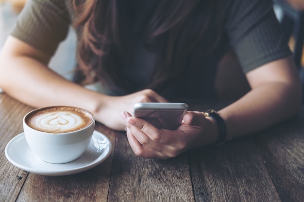 Leute, die Smartphone mit Kaffeetasse verwenden