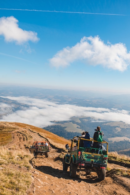 Leute, die suv-autos am berggipfel-kopierraum fahren